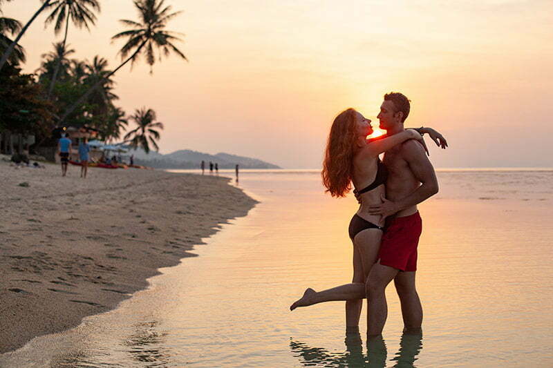 casal feliz na praia com pôr do sol
